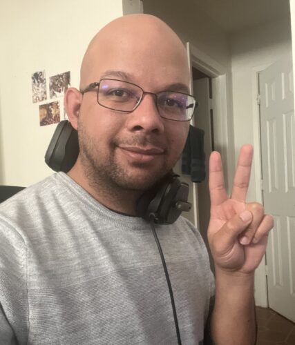 VCFA writing for children and young adult program co-director brandon brown holds up a peace sign.