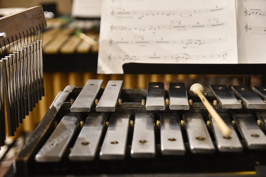 A close up shot of a xylophone and chimes with sheet music in the background