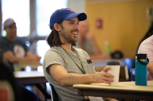 Smiling VCFA MFA in Music Composition student in a classroom looking at the MFA faculty facilitator who is off screen.