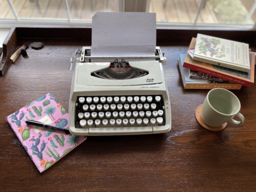 Photo of Rebecca Jamieson's desk, complete with a typewriter, a notebook, and a coffee
