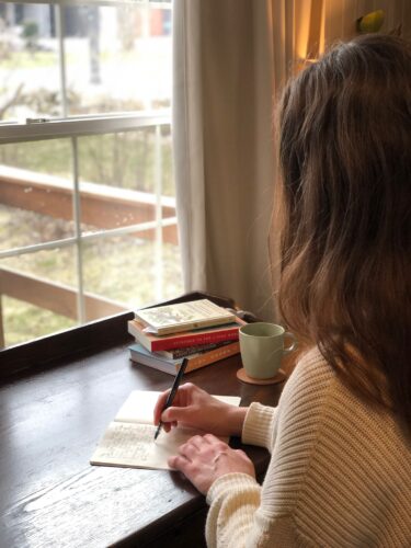 Photo of writer, editor, and VCFA MFA in Writing & Publishing alumnx Rebecca Jamieson writing in a notebook