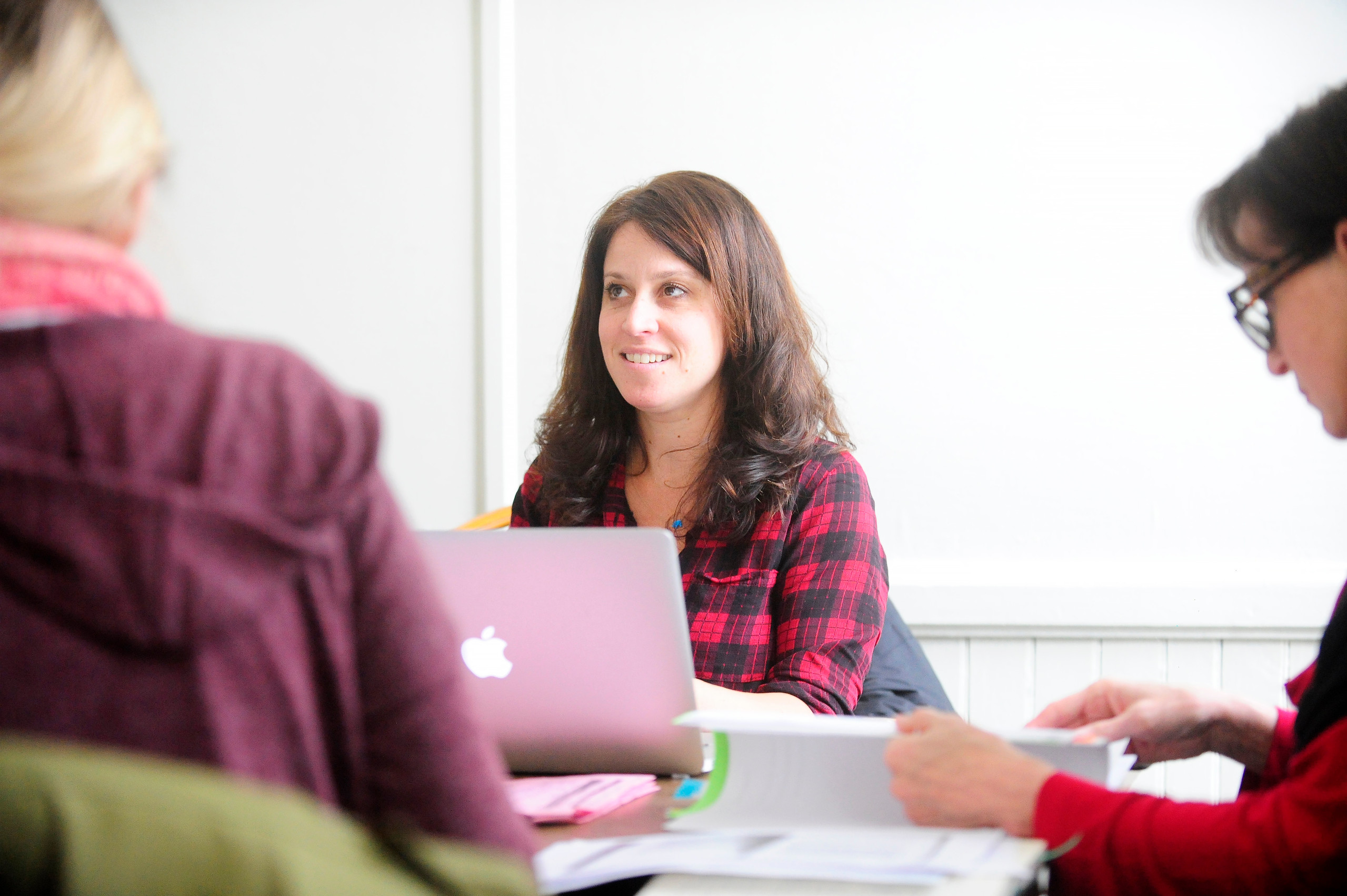 A smiling VCFA student looks to an offscreen colleague as they discuss the best author tools for writing.
