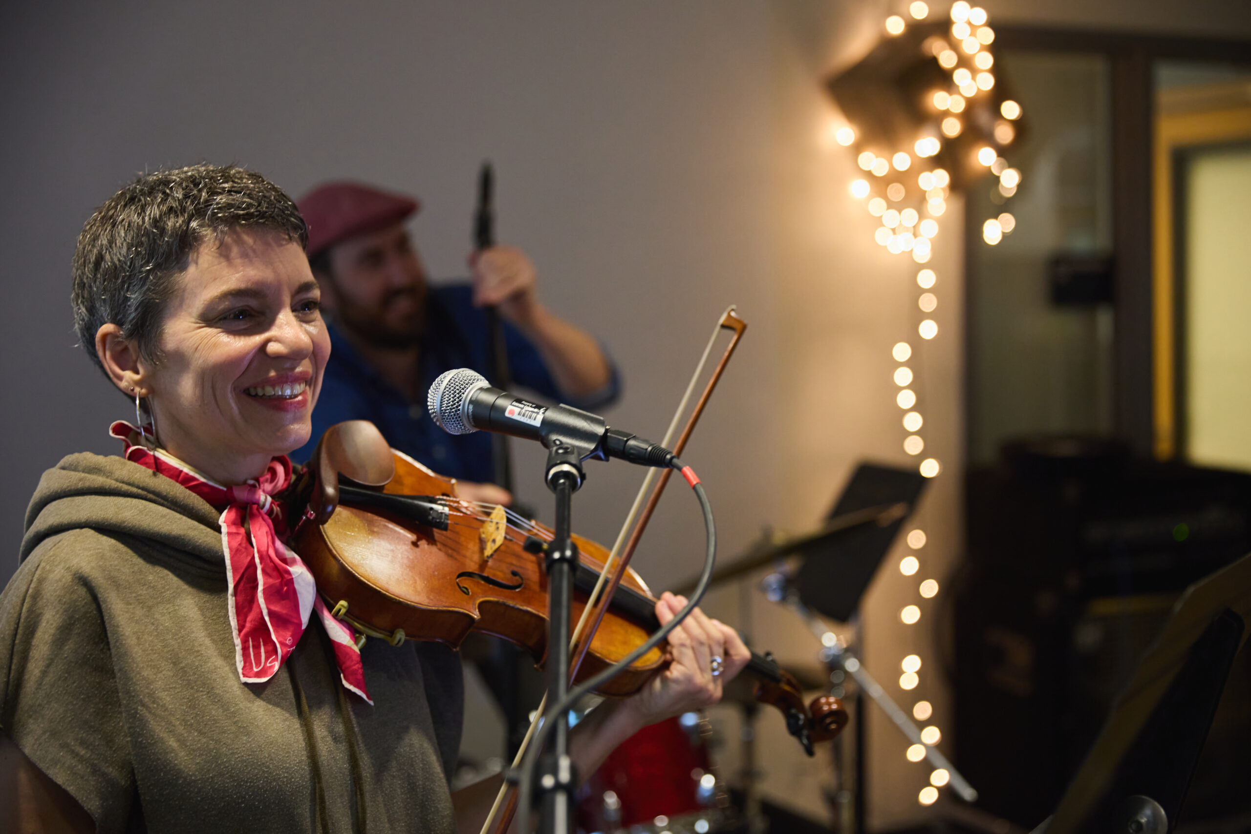 VCFA student smiles while playing the violin for a film scoring lesson.