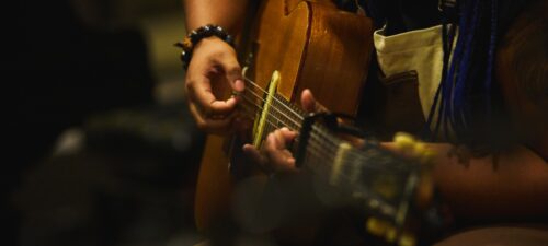 close up of musician playing acoustic guitar