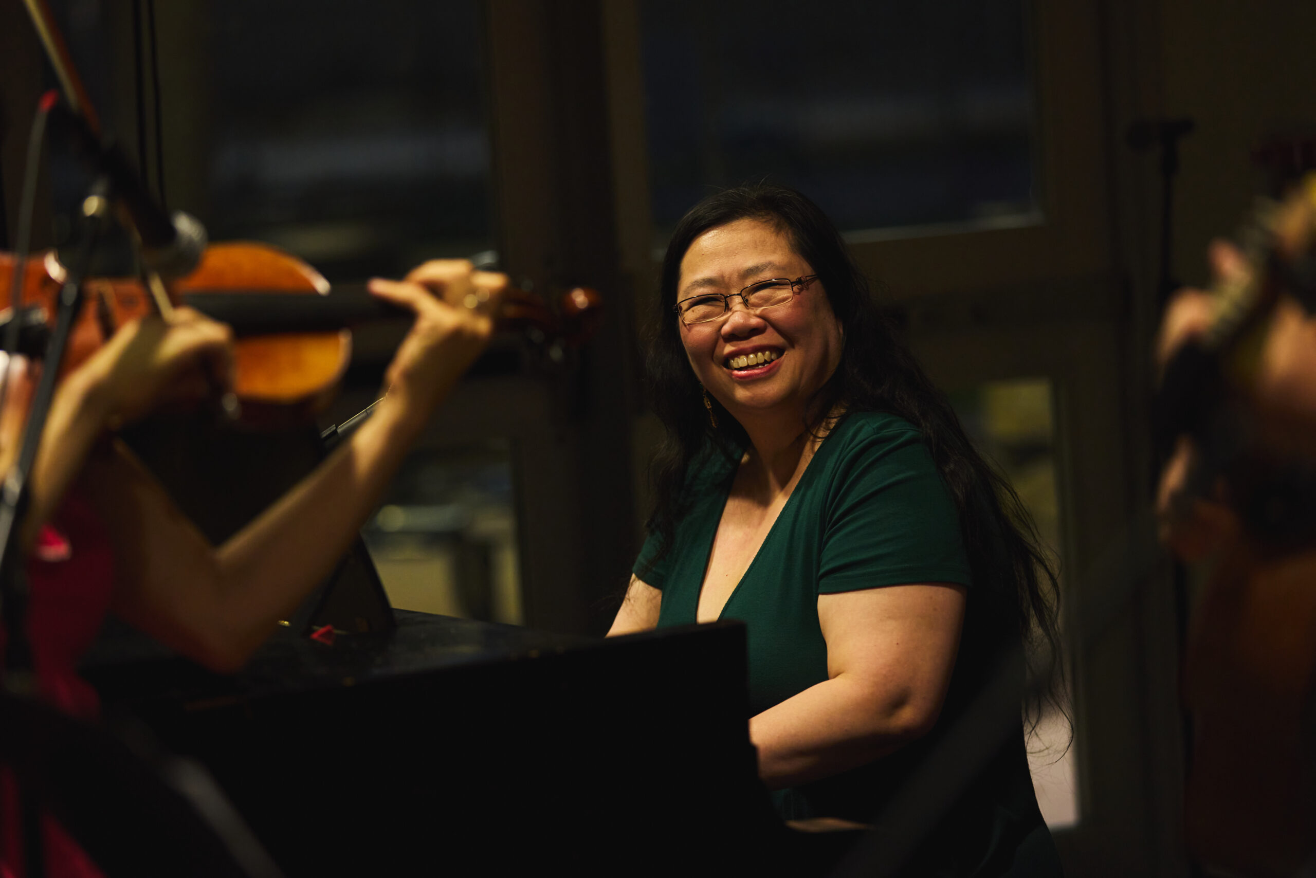 VCFA faculty member smiles while performing at a piano.