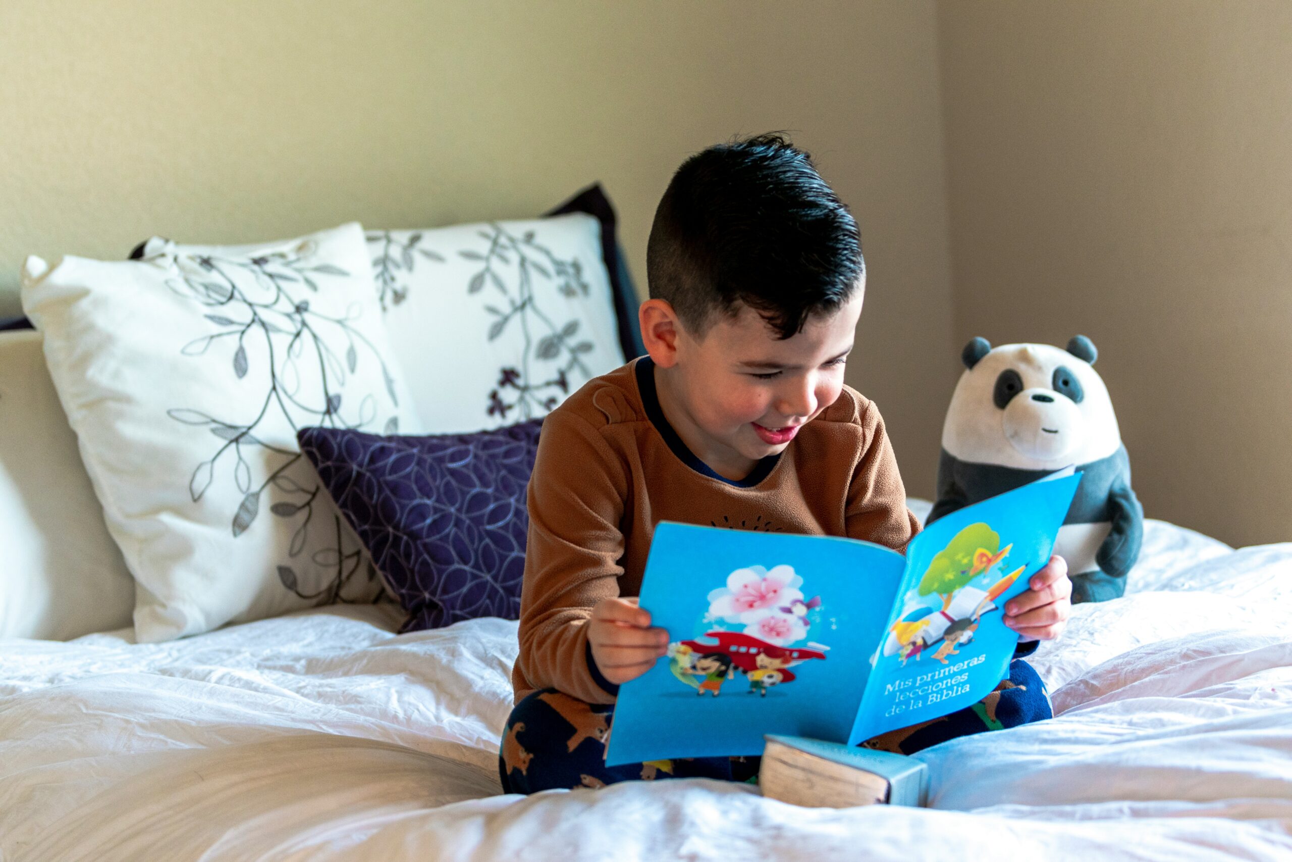 A child smiles while reading a picture book.
