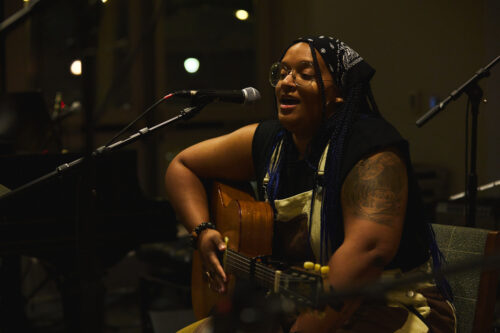 VCFA student sings and plays the guitar during a showcase performance.