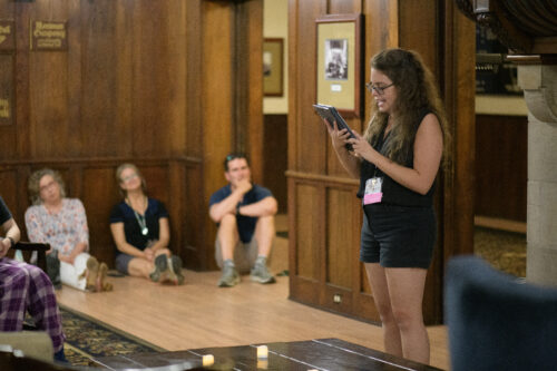 A VCFA student reads aloud to a crowded room during a WCYA residency.